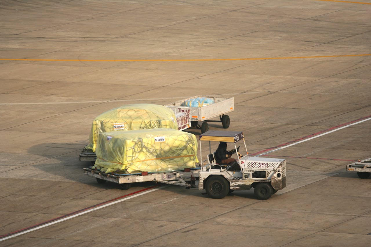 Cargo being handled on the tarmac at Bangkok Airport. Seen from above, this includes trailers and ground staff.